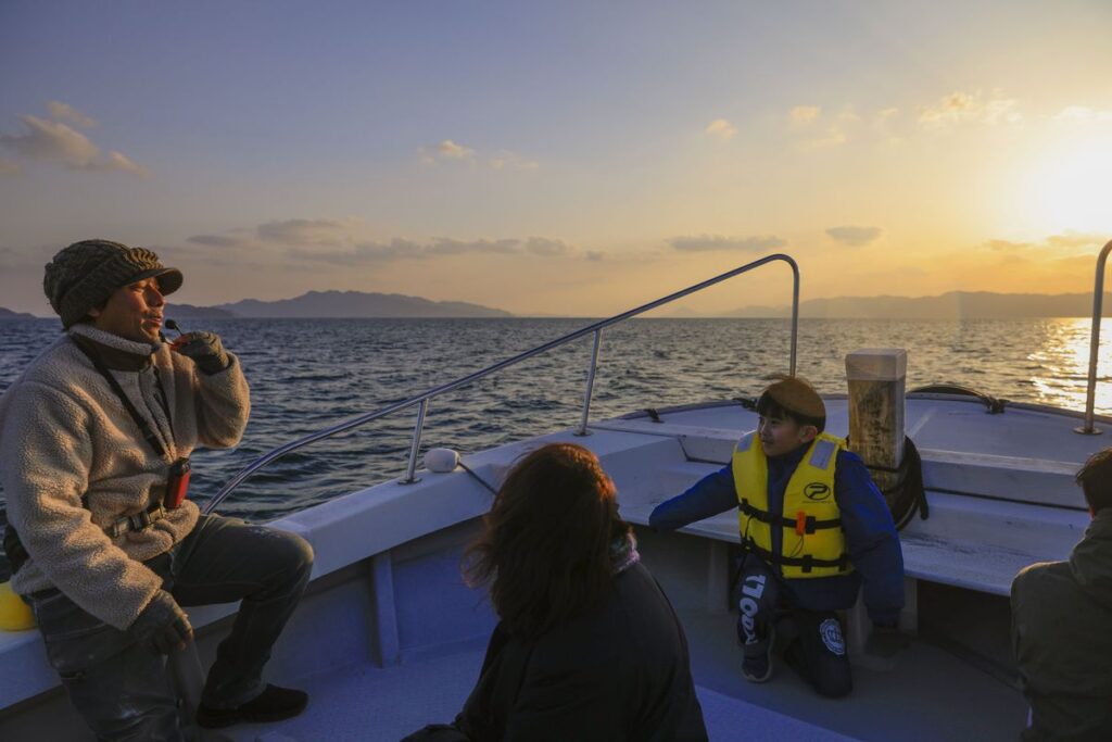 夕暮れの海上タクシーで過ごす船頭と参加者
